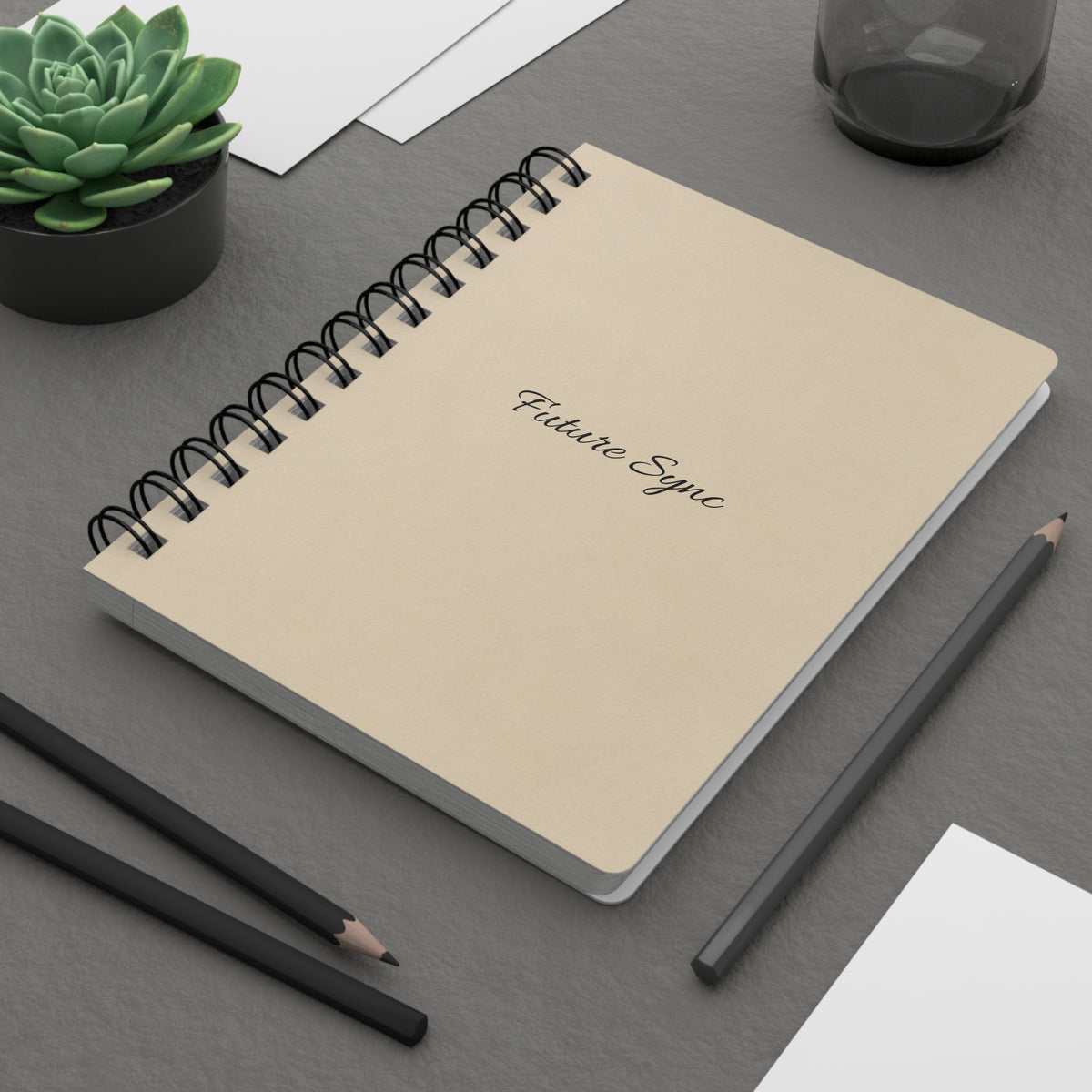 Future Sync beige spiral journal styled on a modern grey desk with pencils and a small plant
