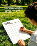 A printed minimalist monthly planner calendar layout placed on green grass outdoors